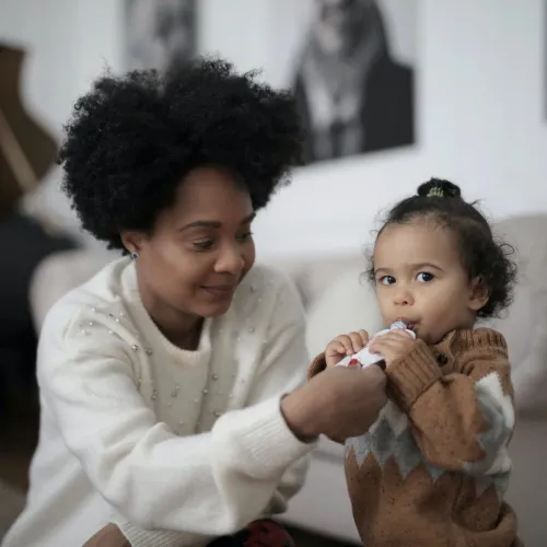 A mother helps to feed her young daughter.