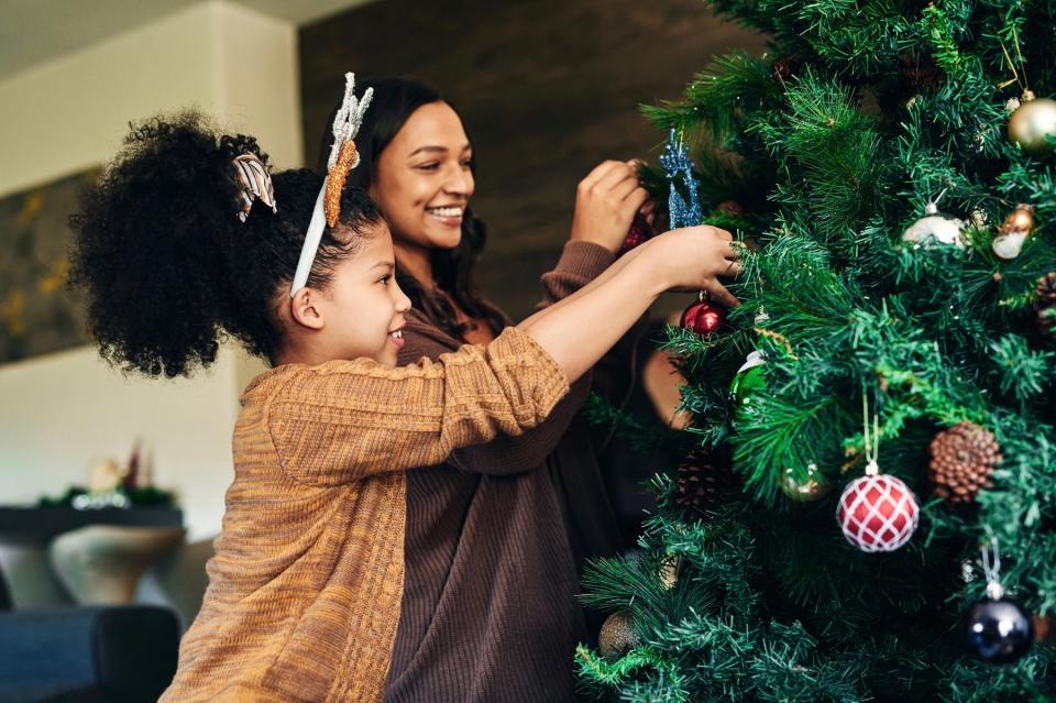 Mom and daughter decorating Christmas tree. 