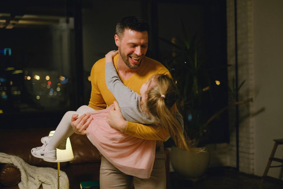 Dad holding his young daughter, smiling.