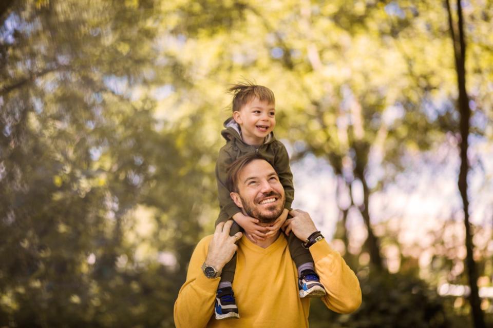 Son sitting on dad's shoulders, smiling.