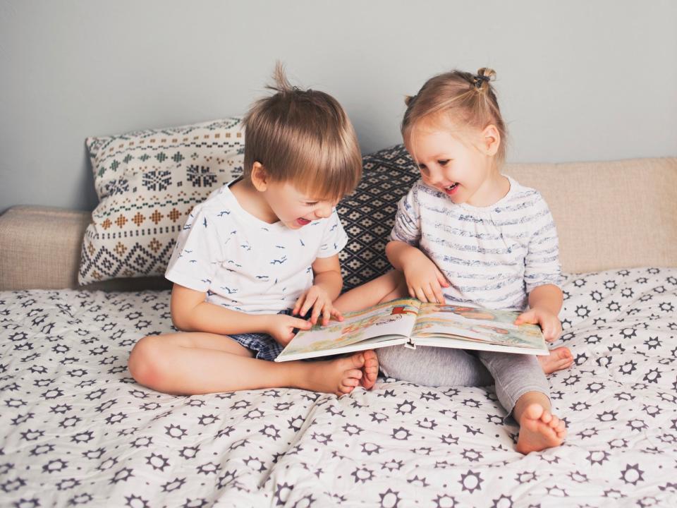 Two little kids sitting in bed reading a book